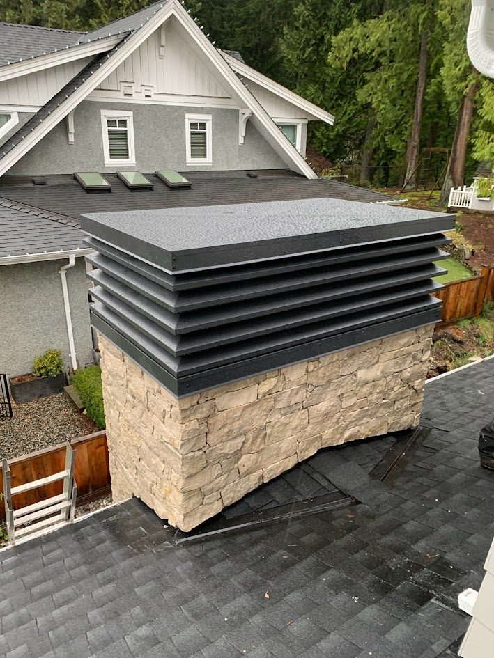 Large louvered chimney enclosure in dark anthracite finish, installed on a stone chimney.
