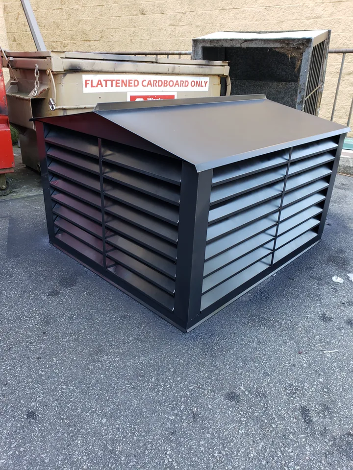 A large black louvered chimney cap outside the shop, with full louvre bands on all four faces and a hipped rain cover sloping to a raised standing edge.